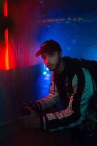 Full length portrait of young man sitting at night