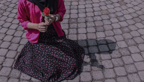 Low section of woman holding umbrella on street