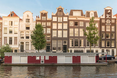 Residential buildings by river against sky