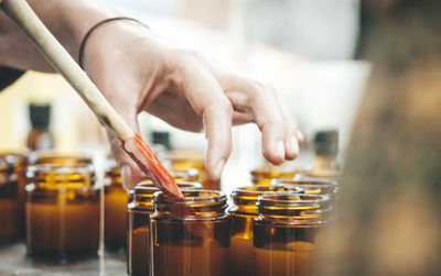 Cropped hands of woman with jars on table