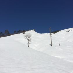 Scenic view of snow covered mountains against clear blue sky