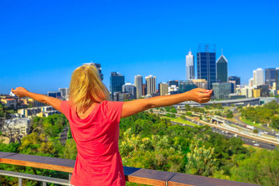 Rear view of woman standing by buildings against clear sky