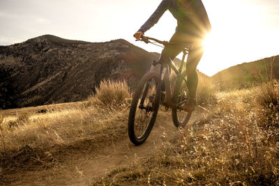 Woman mountain biking during sunset in mountains on single track