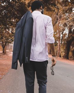 Rear view of man with blazer walking on road