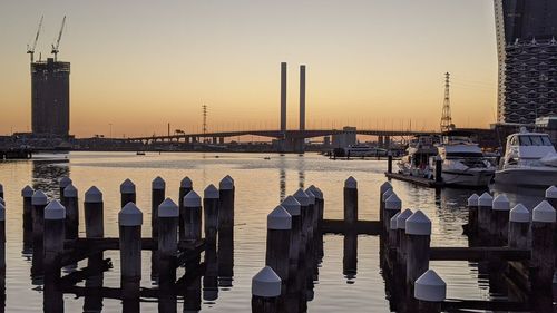 Boats moored in harbor at sunset