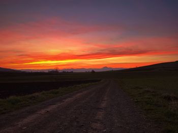 Scenic view of road against dramatic sky during sunset