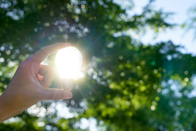 Low angle view of person hand against bright sun
