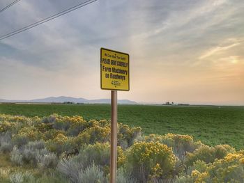 Information sign on field against sky