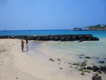 People at beach against clear sky