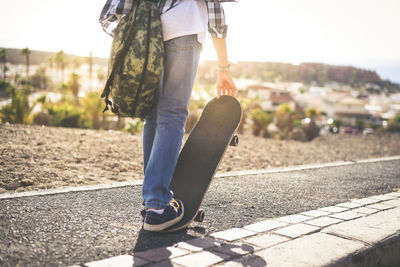 Low section of man skateboarding on road