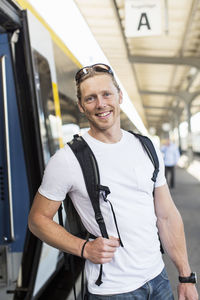 Portrait of happy man standing by metro train at station
