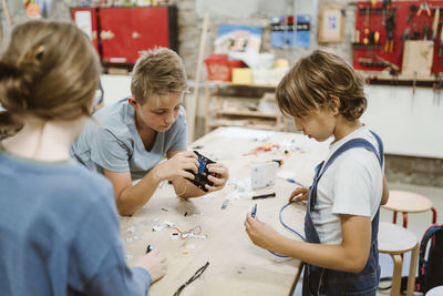 Male and female pupils working on robotics project on table in workshop