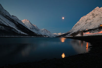 Scenic view of lake and snowcapped mountains against sky at night