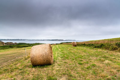 Hay bales on field against sky