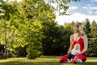 Rear view of women sitting on plants against trees