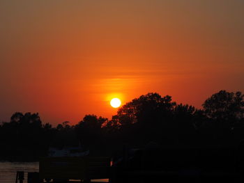 Silhouette trees against orange sky during sunset