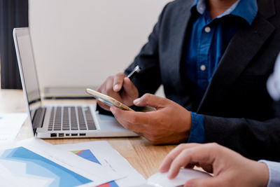 Midsection of man using mobile phone on table