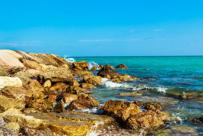 Rock formation on beach against blue sky