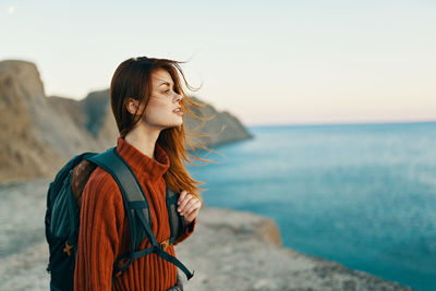 Young woman looking at sea against sky