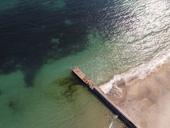 Aerial top down view of old concrete pier or breakwater with emerald sea water