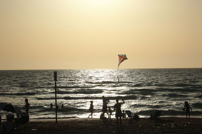 Silhouette man on beach against clear sky during sunset