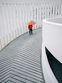 Rear view of person walking with an umbrella on car park concrete ramp