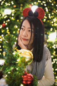 Portrait of young woman holding christmas tree