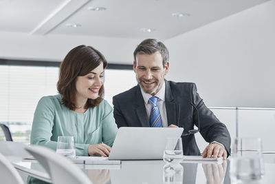 Businessman and businesswoman having a meeting in office with laptop