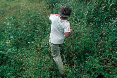 High angle view of boy walking amidst plants on field