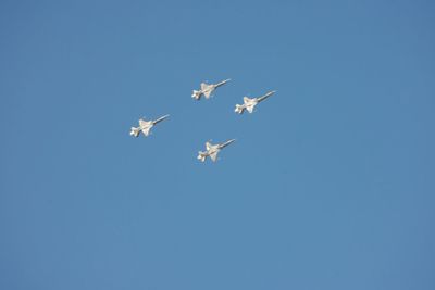 Low angle view of airshow in clear blue sky