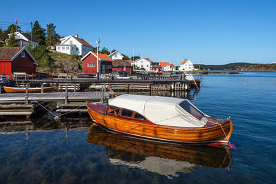 Boat moored on lake by buildings against sky