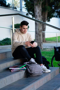 Young man using mobile phone while sitting on steps