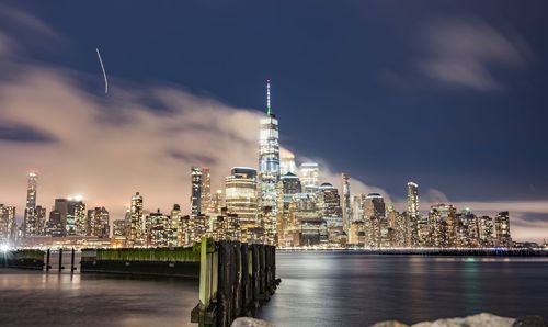 Illuminated modern buildings in city against sky at night