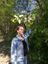 Young woman standing by trees