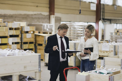 Businessman discussing with female manager in factory warehouse