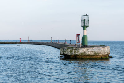 Lighthouse by sea against sky