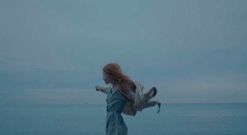 Woman standing in sea against clear sky