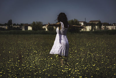 Rear view of woman on field against clear sky