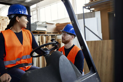 Man talking to female worker on forklift in factory