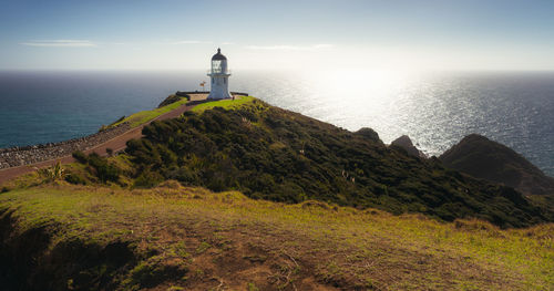 Lighthouse amidst sea and buildings against sky