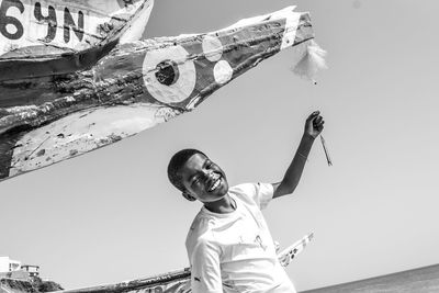 Low angle view of boy with arms raised against sky