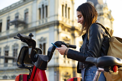 Woman taking a rental electric bike with her cell phone.