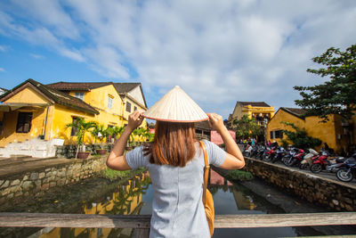 Rear view of woman with umbrella standing against sky