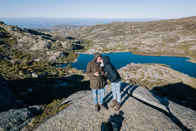 Couple kissing while standing on mountain against clear sky