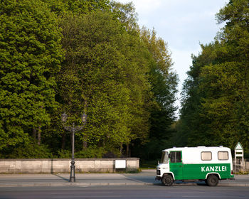 Van moving on road by trees