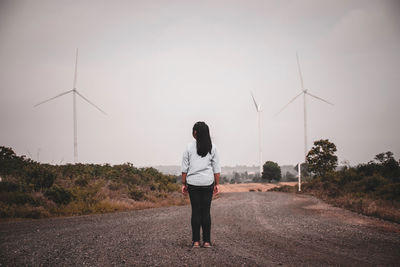 Rear view of woman standing on road against sky