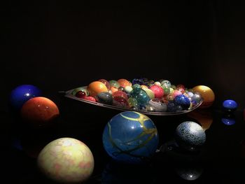 Close-up of multi colored balls on table against black background