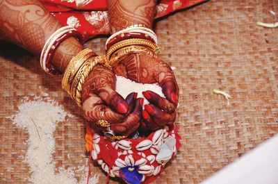 Cropped hands of bride holding rice on mat