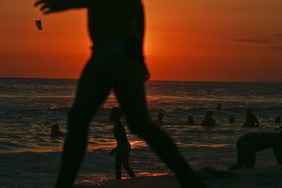 Silhouette people in sea during sunset