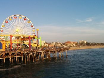 Ferris wheel by sea against sky